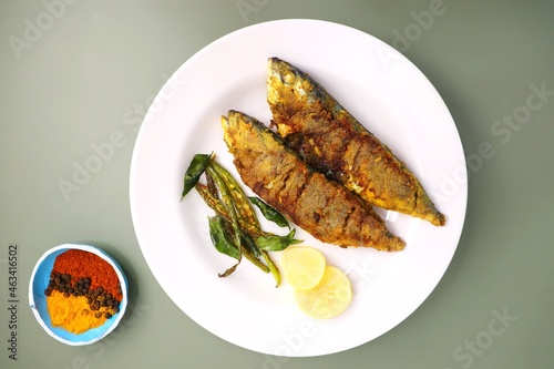 Indian Mackerel fish fry. Bangda Rava fry. whole Fried fish served on a banana leaf with fried chilies, lemon slices, and Indian spices. also known as talalele bangde in Marathi. Copy space. photo