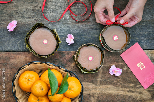 Top view of hands tying ribbon on sweet sticky rice cake also known as Nian Gao on wooden table.