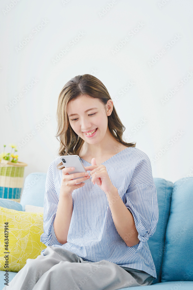 部屋でスマホを使う女性 部屋でスマホを使う女性