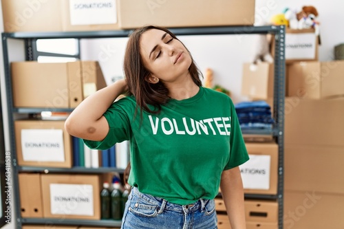 Young brunette woman wearing volunteer t shirt at donations stand suffering of neck ache injury  touching neck with hand  muscular pain