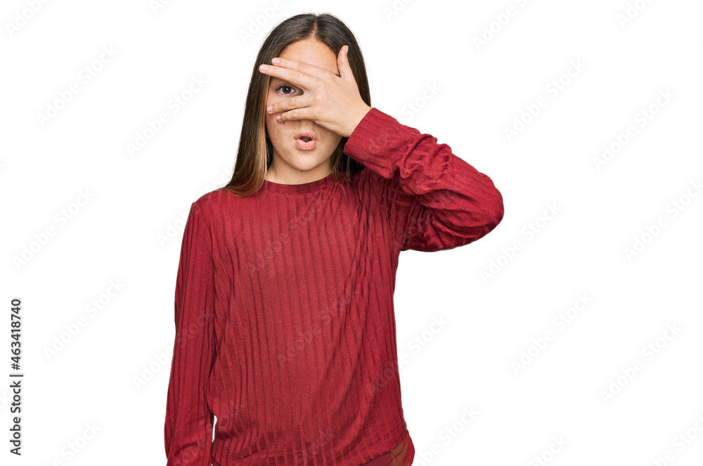 Beautiful brunette little girl wearing casual sweater peeking in shock covering face and eyes with hand, looking through fingers with embarrassed expression. Beautiful brunette little girl wearing casual sweater peeking in shock covering face and eyes with hand, looking through fingers with embarrassed expression.