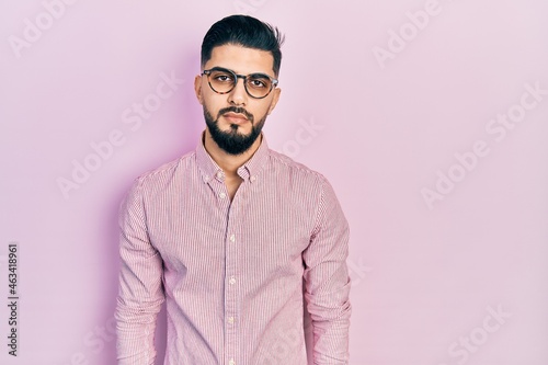 Handsome man with beard wearing casual shirt and glasses with serious expression on face. simple and natural looking at the camera. © Krakenimages.com