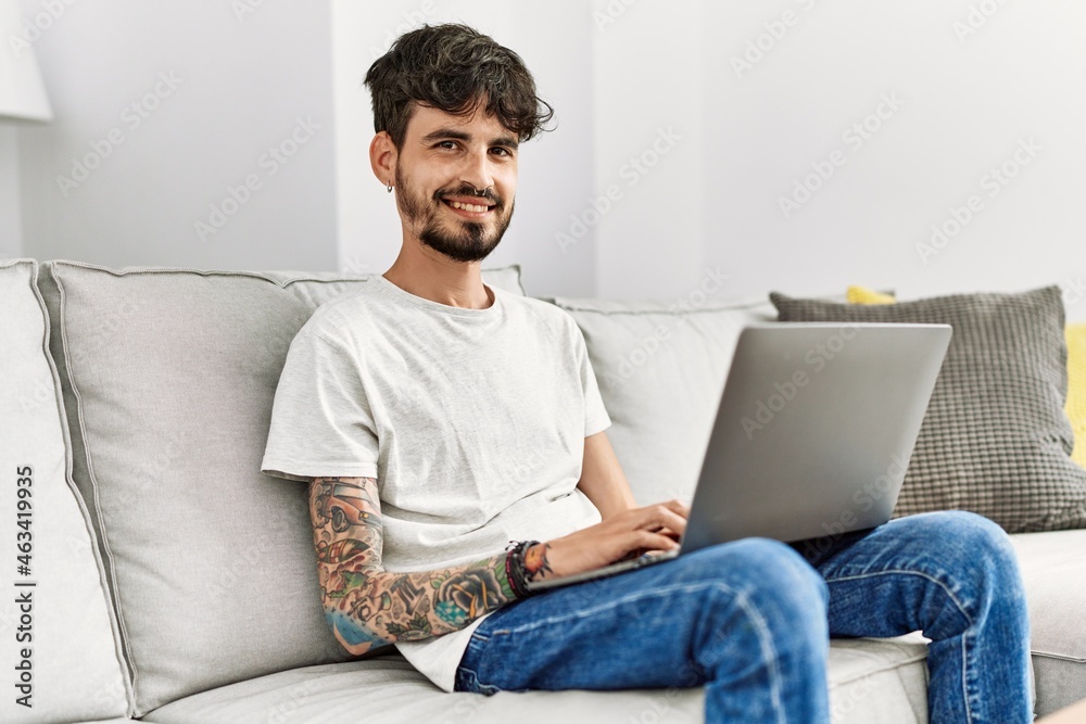Young hispanic man using laptop sitting on the sofa at home. Young hispanic man using laptop sitting on the sofa at home.