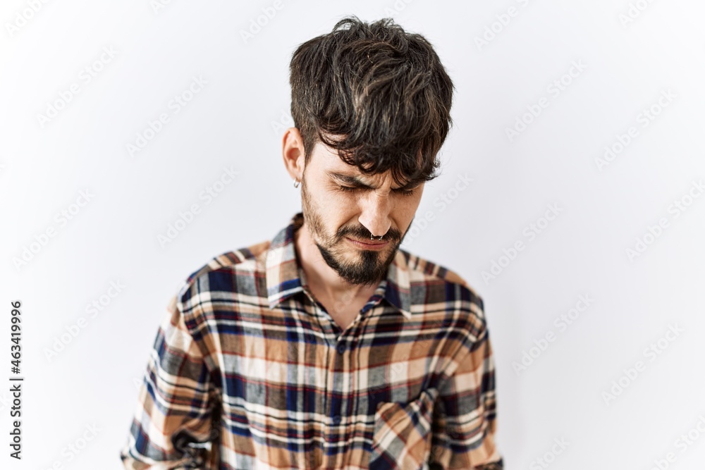 Hispanic man with beard standing over isolated background with hand on stomach because nausea, painful disease feeling unwell. ache concept. Hispanic man with beard standing over isolated background with hand on stomach because nausea, painful disease feeling unwell. ache concept.
