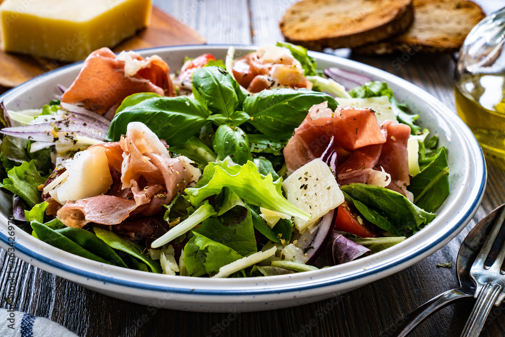 Tasty salad - prosciutto di Parma, parmesan and fresh, green vegetables on wooden table
 - obrazy, fototapety, plakaty 