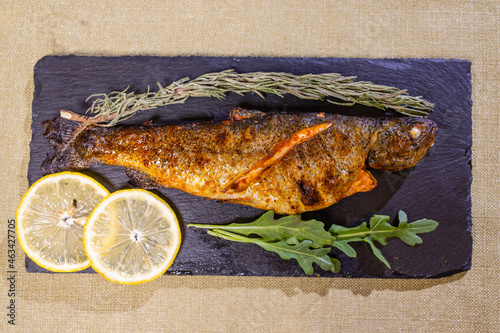 Roasted gilthead fishes with lemon, herbs, salt on black background. Healthy food concept. Food frame. photo