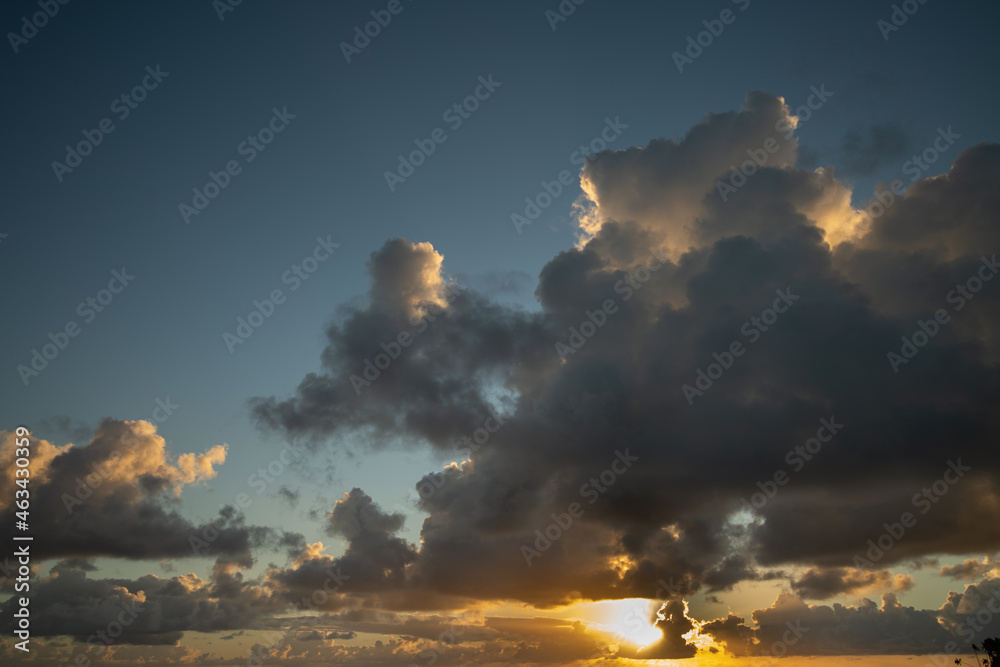 sun behind clouds close up creating abstract view of detail in clouds blue sky grey and white clouds fluffy contrast light from sun heavenly glow from sunlight shining through cloud horizontal format 