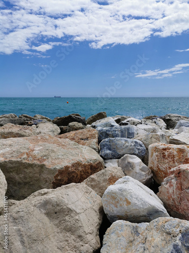 Vertical view of the Mediterranean sea hitting rocks on the beach.