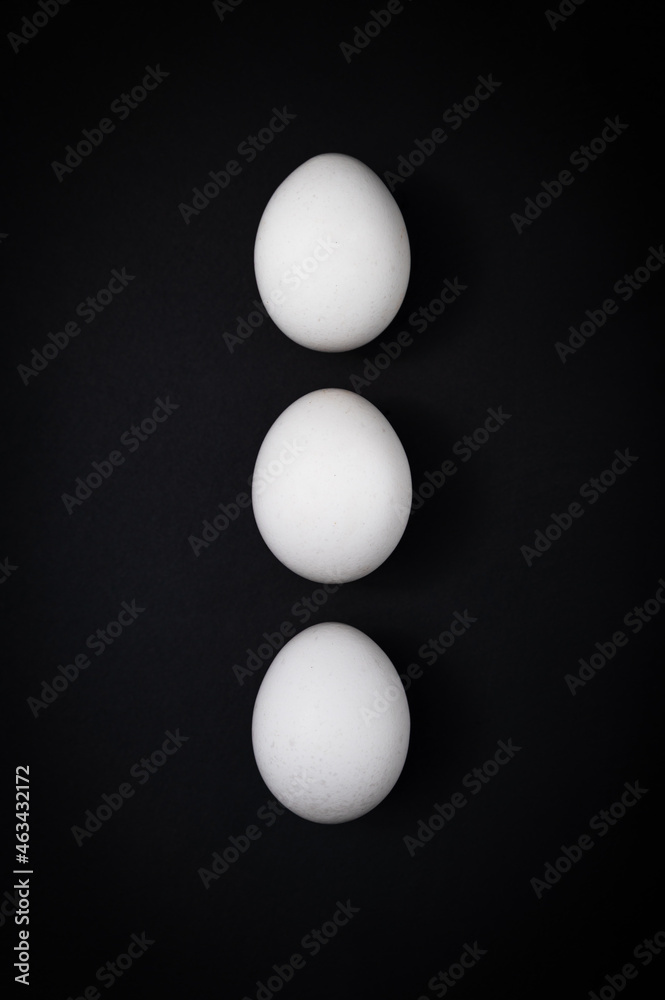 Breakfast triple: three white chicken eggs against a dark slate background. Table top view, flat lay, copy space. Breakfast triple: three white chicken eggs against a dark slate background. Table top view, flat lay, copy space.