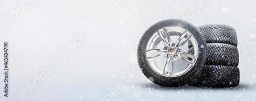 a set of winter tires and alloy wheels on a snowy white background. driving safety in winter and seasonal tire change in icy conditions photo