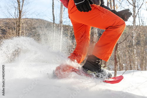 Snowshoes walking in snow. Closeup of legs of man athlete running in white deep powder snow snowshoeing wearing snowshoe boot. photo