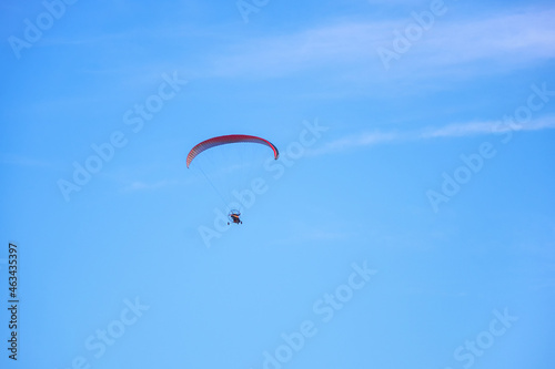 Colorful powered paraglider against blue sky. Paragliding concept, horizontal photo