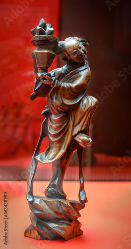 A 19th-century Chinese sculpture made of wood depicting a dancing Lan Caihe with a basket of flowers in his hands photo