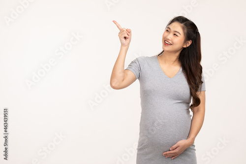 Happy Pregnant Woman standing smile stroking big belly with love and pointing on copy space isolated on white background,Pregnancy of young woman enjoy with future life,Motherhood and Pregnant Concept