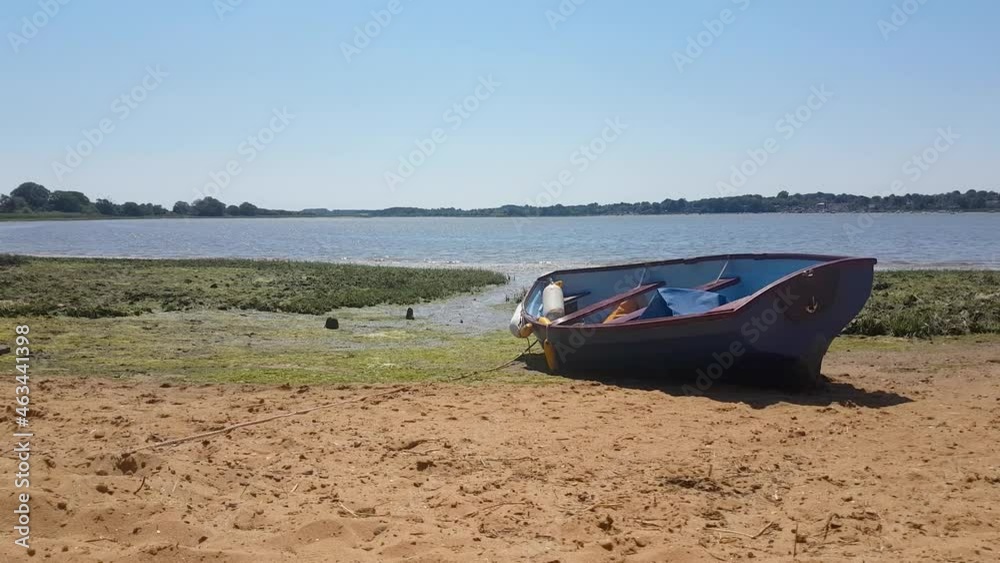 A row boat grounded on a sandy beach with a clear blue summer sky and high tide in the background A row boat grounded on a sandy beach with a clear blue summer sky and high tide in the background