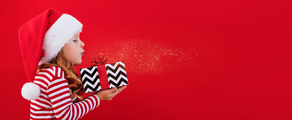 Christmas banner child in a santa hat holding a gift on a red background with place for text