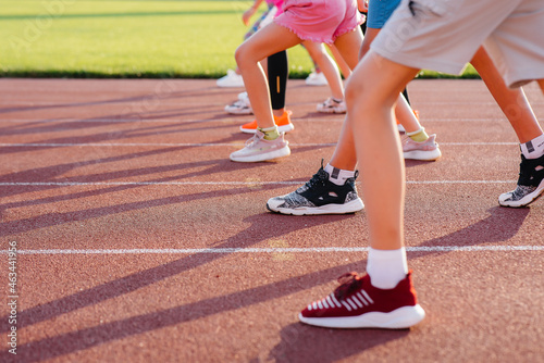 Close-up of the legs of children running around in the stadium with a large company. A healthy lifestyle.