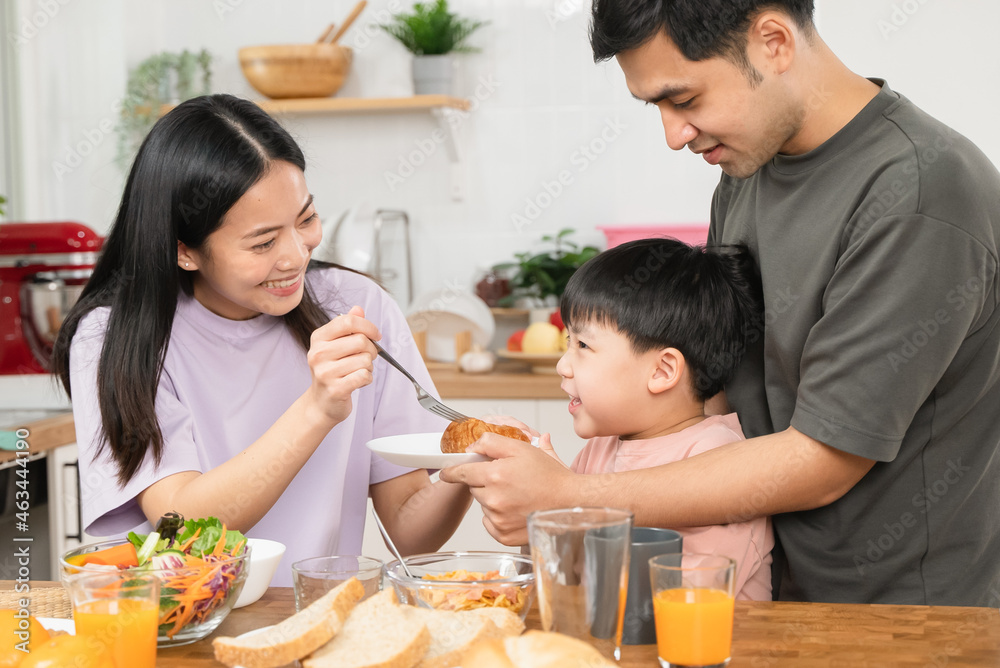 happy family together. Asian parent eating breakfast with little son in the kitchen. happy family together. Asian parent eating breakfast with little son in the kitchen.