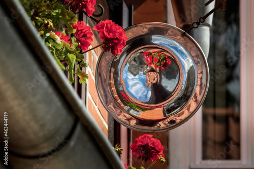 in einem runden Teller am Haus spiegelt sich die Straße der Altstadt umrahmt von Blüten