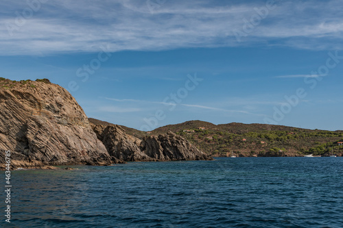 Seaside cliffs, sailboats and houes in Guillola Bay next to Cadaques and Cap Creus, Catalonia, Spain