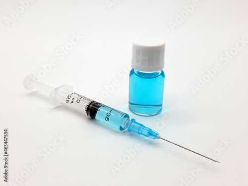 A syringe and a vial filled with a covid-19 vaccine for innoculation of the population. Blue liquid symbolizing the vaccine. photo