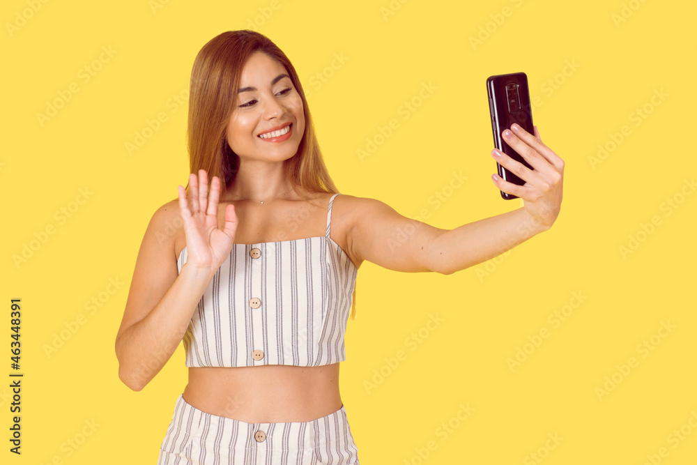 Young Latina woman isolated using her cell phone. Lifestyle concept. Dressed in a summery outfit. Space for text. Young Latina woman isolated using her cell phone. Lifestyle concept. Dressed in a summery outfit. Space for text.