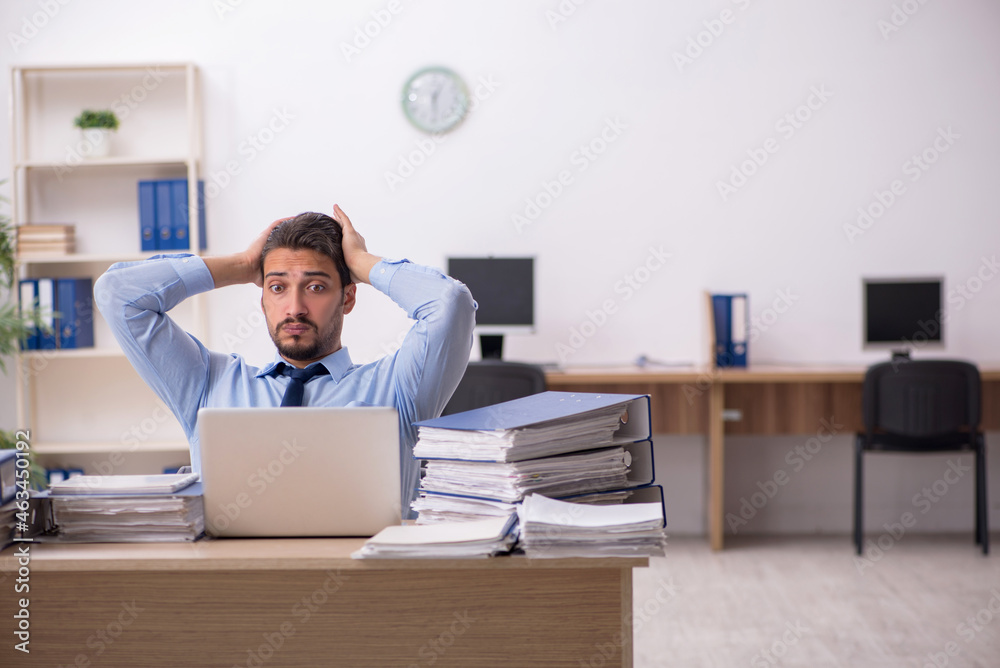 Young male employee and too much work in the office Young male employee and too much work in the office