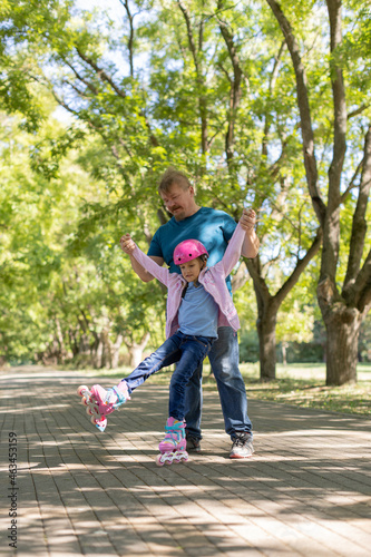 Fototapeta Naklejka Na Ścianę i Meble -  dad teaches daughter to roller skate