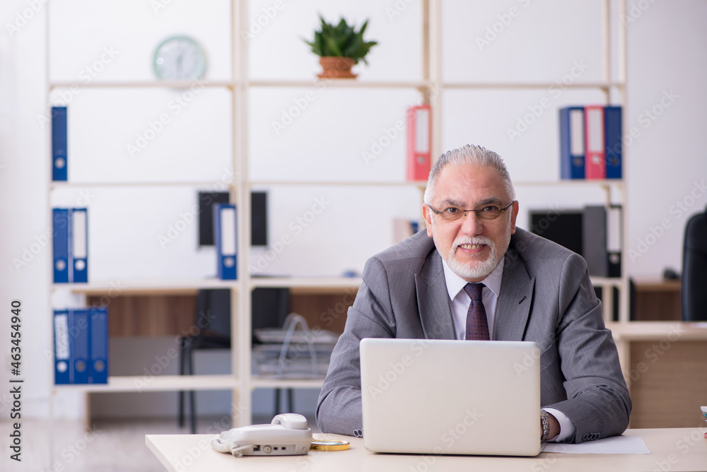 Old male employee unhappy with excessive work in the office Old male employee unhappy with excessive work in the office