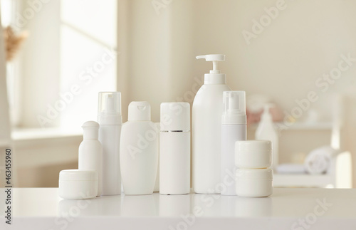 Cosmetic skin care products of new female bodycare line for health  beauty and wellbeing. White mockup lotion bottles  cream jars and soap dispenser standing in row on table or shelf in beauty parlour