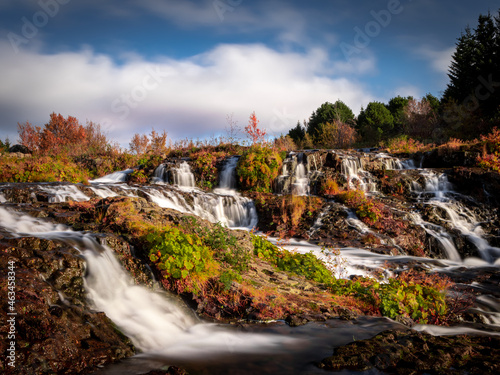 Kermoafoss waterfall surrounded by the forest in Reykjavik, Iceland. Vibrant autumnal colours. Long exposure photo. 