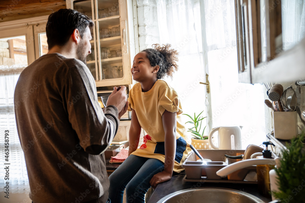 Cheerful father and his daughter having breakfast together in the kitchen Cheerful father and his daughter having breakfast together in the kitchen