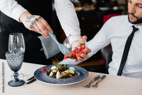 Принти на полотні The waiter makes an exquisite serving of seafood salad, tuna and black caviar in a beautiful serving on the table in the restaurant