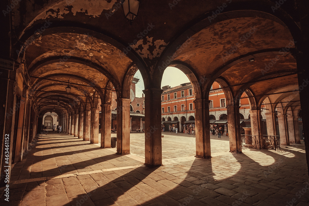 Old arches of historical square with bars and restaurants in famous european city Venice.