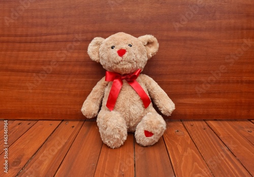 teddy bear with red bow on wooden background 