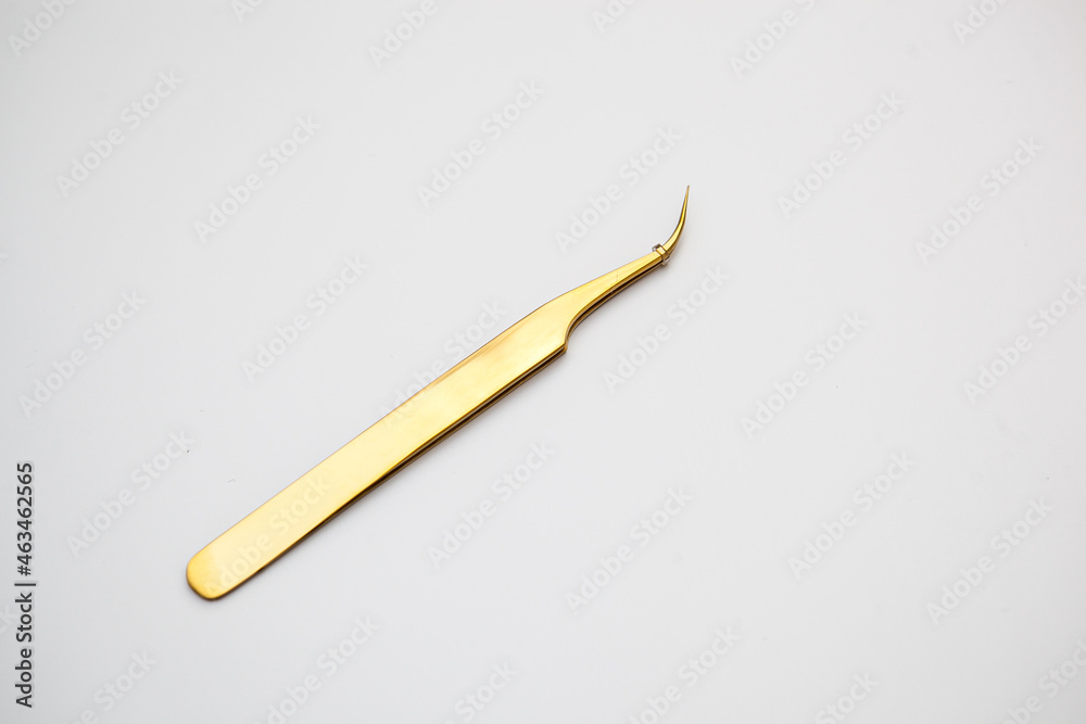 tools for eyelash extensions and eyebrow design. cosmetic tweezers in gold color on a white background tools for eyelash extensions and eyebrow design. cosmetic tweezers in gold color on a white background