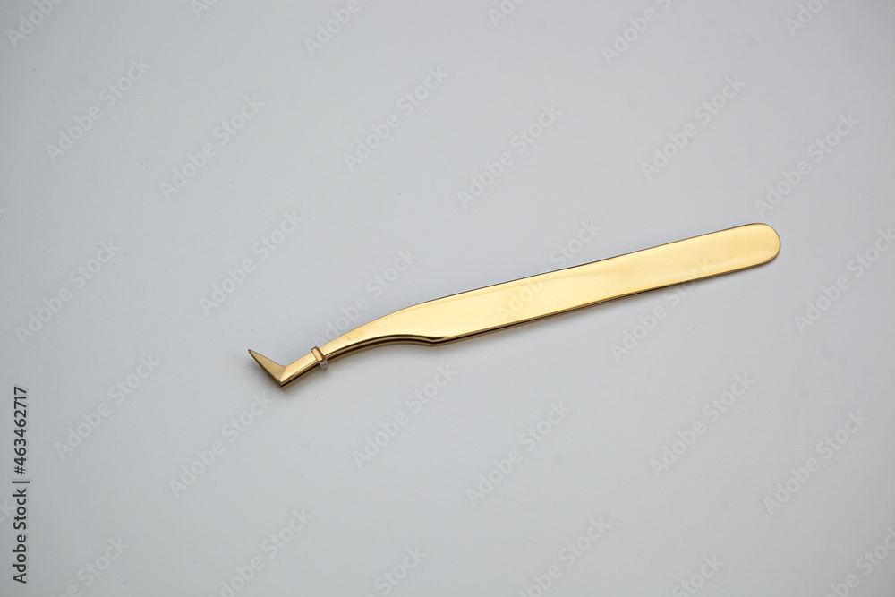 tools for eyelash extensions and eyebrow design. cosmetic tweezers in gold color on a white background tools for eyelash extensions and eyebrow design. cosmetic tweezers in gold color on a white background
