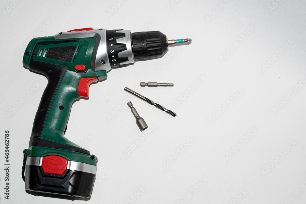 Manual power tool, for work on tightening screws, screws, drilling holes, milling surfaces. Green drill - screwdriver equipped with a variety of nozzles, on a white background. A tool for manual work. Manual power tool, for work on tightening screws, screws, drilling holes, milling surfaces. Green drill - screwdriver equipped with a variety of nozzles, on a white background. A tool for manual work.