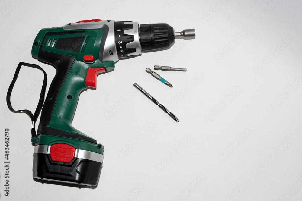 Cordless drill - screwdriver, with attachments, on a white background. Green screwdriver, equipped and ready to work, photo on a white background. A tool for manual work. Cordless drill - screwdriver, with attachments, on a white background. Green screwdriver, equipped and ready to work, photo on a white background. A tool for manual work.