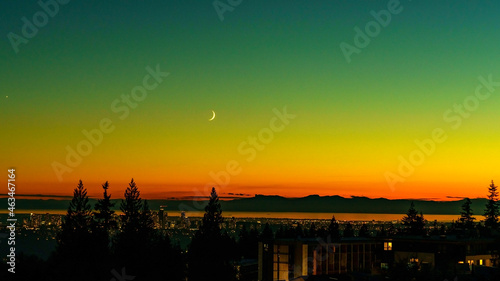 Beautiful BC sunset with crescent moon over distant Straits of Georgia and Gulf Islands as viewed from Burnaby Mountain.