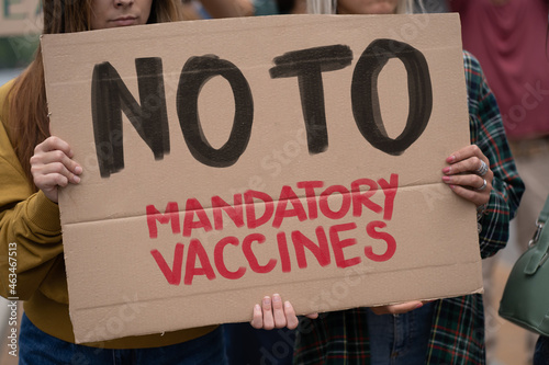 Group of no VAX deniers holding up a "no to mandatory vaccines" sign during the covid-19 pandemic © Lomb