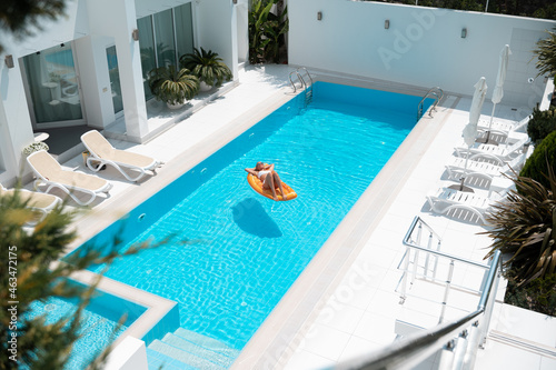 woman on the mattress swims in the pool on villa