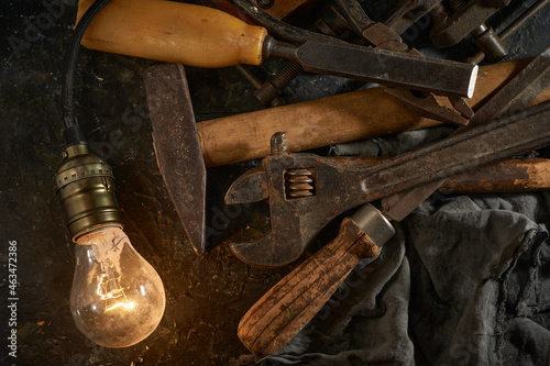 Wooden tool box of used hand tools with old and dirty, rusty wrenches, hammers, and old light bulb
