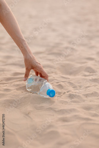 a man collects plastic bottles and garbage on the beach in a public place. eco friendly and caring for nature. collect plastic muslr and take it for recycling. careful attitude to the planet