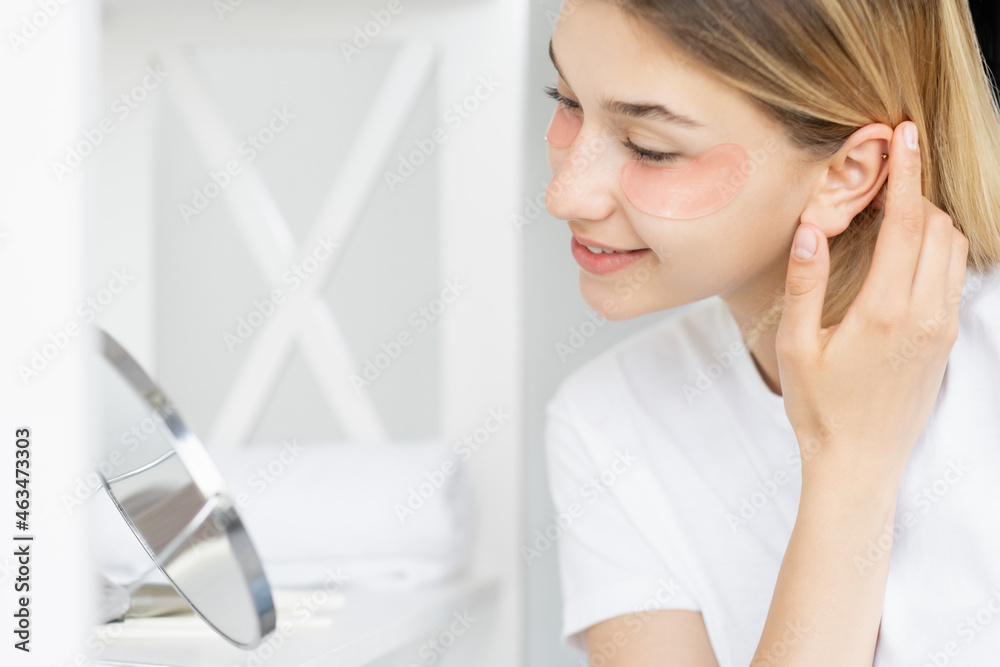 Morning pampering. Anti-aging treatment. Beauty wellness. Satisfied woman with under eye patches healthy fresh face skin at mirror in bathroom. Morning pampering. Anti-aging treatment. Beauty wellness. Satisfied woman with under eye patches healthy fresh face skin at mirror in bathroom.