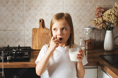 Obraz na płótnie Little girl have a snack with nuts bar and milk