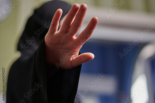 Photography A Muslim woman in traditional black clothing nikab showing stop hand gesture