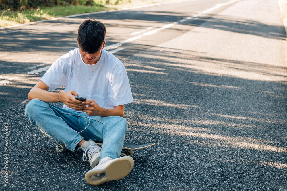 Fototapeta premium boy with skateboard and headphones on the road