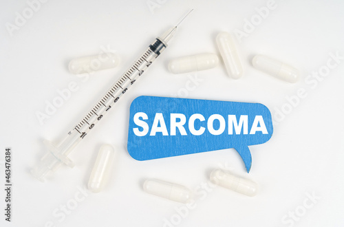 On a white background pills, a syringe and a blue plate with the inscription - SARCOMA photo