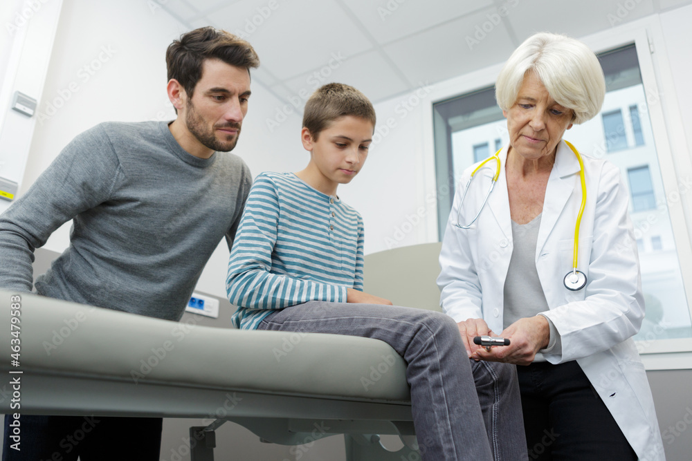 Fototapeta premium senior female therapist examining boy with reflex hammer